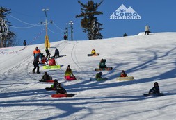 Youth with snowboards sitting on Como Park Ski Hill taking part in lessons. 