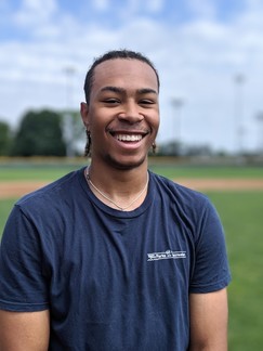 Parks and Recreation employee smiling on a baseball field