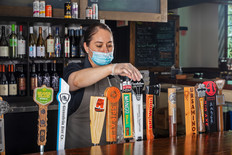 Staff wearing mask pours a beverage at Dock and Paddle.