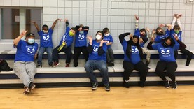 Youth and staff doing silly poses and wearing mask in a gym. 