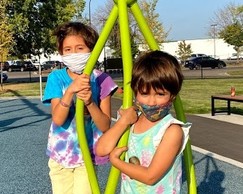 Two youth wearing masks on a playground