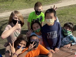 Youth wearing masks outdoors giving the thumbs up sign.