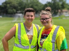 Two Parks Worker I staff on a soccer field in high visibility safety vests.