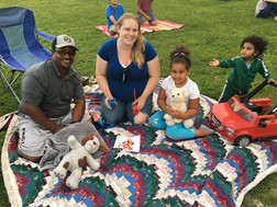 Family on a blanket on the grass watching an outdoor movie
