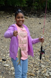 Youth on Hidden Falls beach smiling holding up a fish