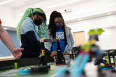 Two youth working on a robot during a robotics competition. 