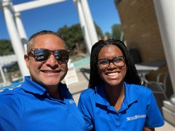 Two lifeguards smiling and wearing blue shirts.