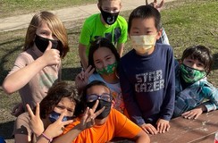 Youth wearing masks pose for the camera around a picnic table.