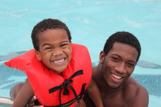 Father and son in a pool smiling.