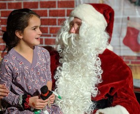 Youth sitting on Santa's lap and smiling. 