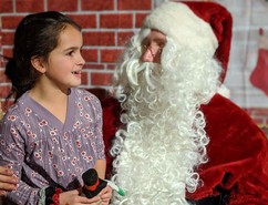 Youth sitting on Santa's lap and smiling. 