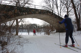 Cross country skiers skiing under a bridge