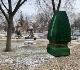 Small, wooden evergreen tree near a playground.