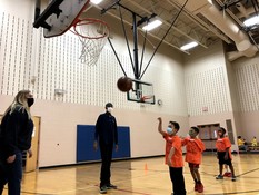 Youth playing basketball in a gym. 