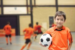 Youth wearing an orange shirt holding a soccer ball 