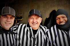 Three sports officials smiling. 