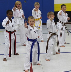 Youth giving a thumbs up during a martial arts class in a gym. 