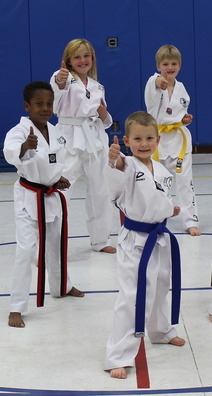 Youth giving a thumbs up during a martial arts class in a gym. 