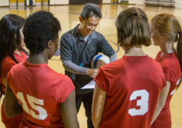 Youth volleyball team and coach in a gym. 