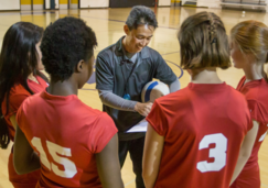 Youth volleyball team and coach in a gym. 