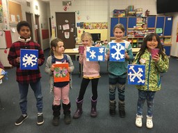 Youth holding up snowflake paintings