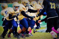 Youth wearing gold and blue uniforms playing football