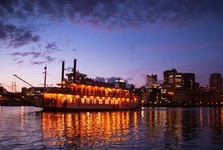 Riverboat with a purple sunset and night skyline in the background. 