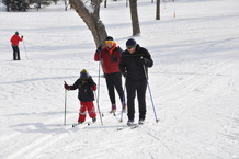 Two adults and one child cross-country skiing
