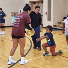 Youth boy being instructed at a volleyball clinic 