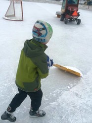 Youth child helping to clear snow at ice rink