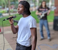 Singer with microphone at Music in the Parks performance in Mears park