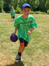 Kid running with ball outside and smiling 