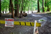 Trail flooding from Mississippi river with "Closed" sign and barricade 