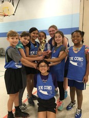 Youth basketball players smiling with a trophey
