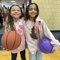 Two sisters holding basketballs and smiling_square cropped photo