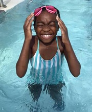 Youth in pool wearing goggles on head and smiling