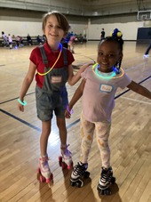 Two youth roller skating on gym floor
