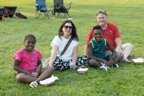 Family sitting on grass at Music in the Parks event