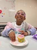 Youth smiling with Valentine's themed decorated cupcake 
