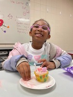 Youth smiling with Valentine's themed decorated cupcake 