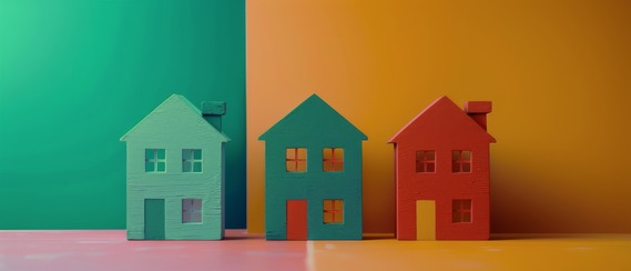 Three colorful wooden house models in green, teal, and red against a split green and orange background.