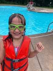Youth girl with goggles standing next to the pool