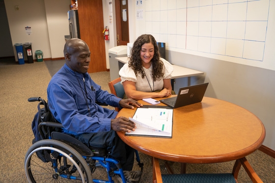 Two people sit at a desk looking at a computer
