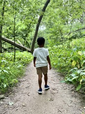 Youth walking on trail in green woods