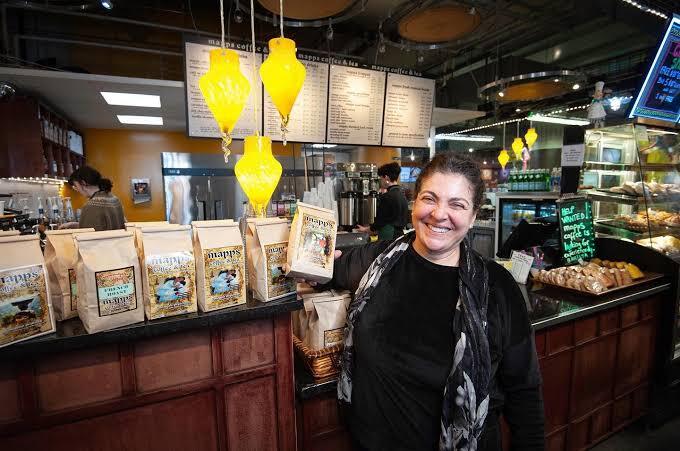 Woman smile while holding bag of coffee in shop