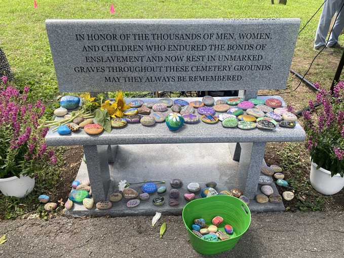 image of memorial bench with memorial stones and flowers