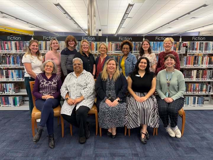 2026 Library Staff In Front of Bookshelves in Library