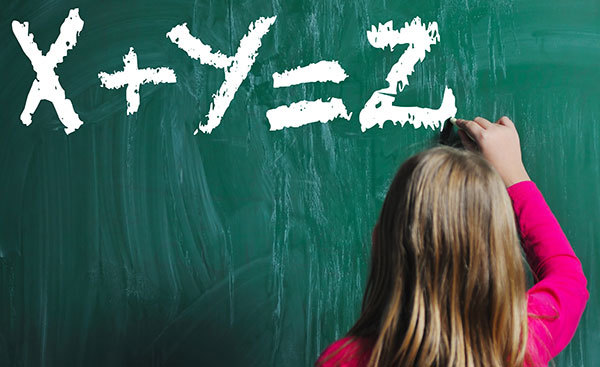Photo of a girl writing a formula on a blackboard: X+Y=Z