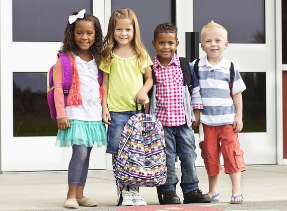 Smiling elementary school children standing outside school entrance