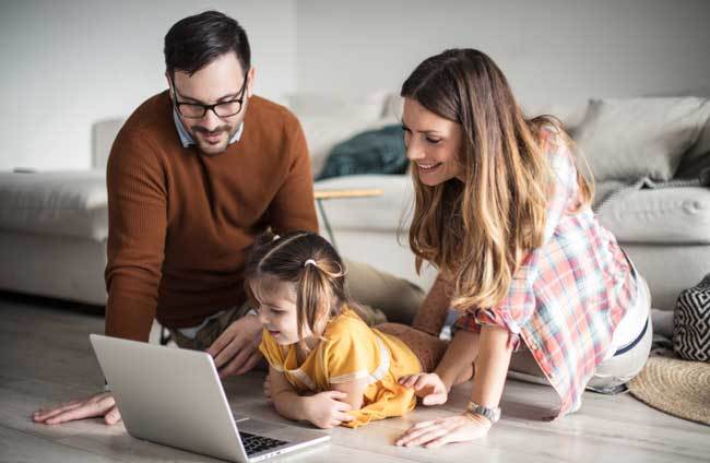 Mother, father and small girl look at a laptop computer